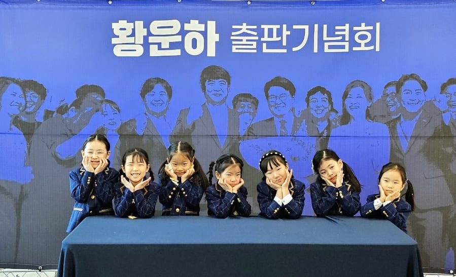 출판기념회 현수막 앞에서 턱을 괴고 웃는 선율반 단원들
