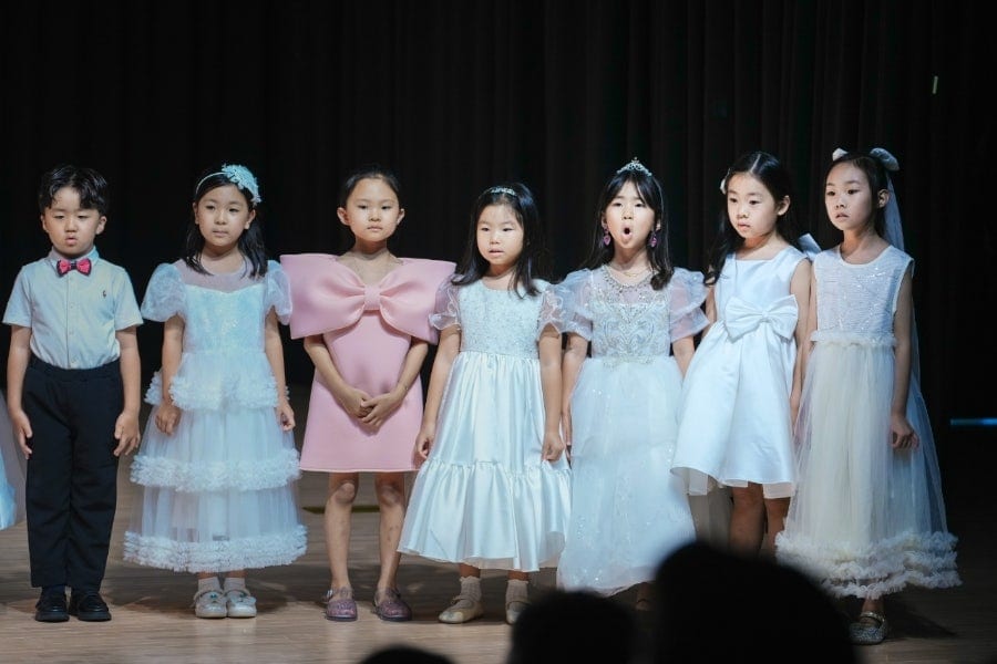 향상음악회 무대에서 드레스를 입고 노래하는 어린이 단원들